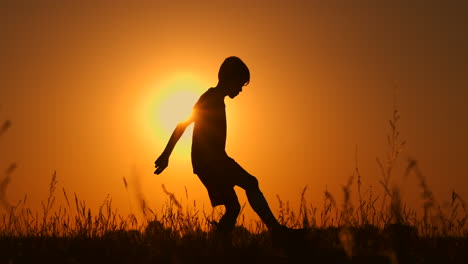 Silhouette-Eines-Jungen,-Der-Bei-Sonnenuntergang-Fußball-Spielt.-Ein-Junge-Jongliert-Bei-Sonnenuntergang-Auf-Dem-Feld-Mit-Einem-Ball.